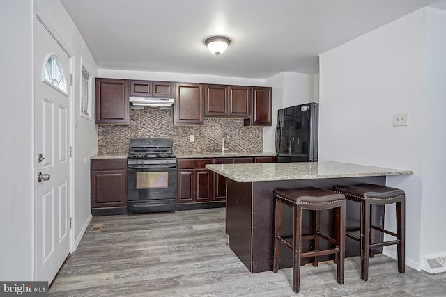 1549 S 8th St, Camden, NJ 08104 - kitchen featuring black range with gas cooktop, fridge, light wood-type flooring, and under cabinet range hood