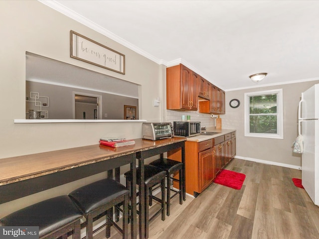 12535 Rockdale Rd, Clear Spring, MD 21722 - kitchen with stainless steel microwave, freestanding refrigerator, brown cabinetry, wood finished floors, and ornamental molding
