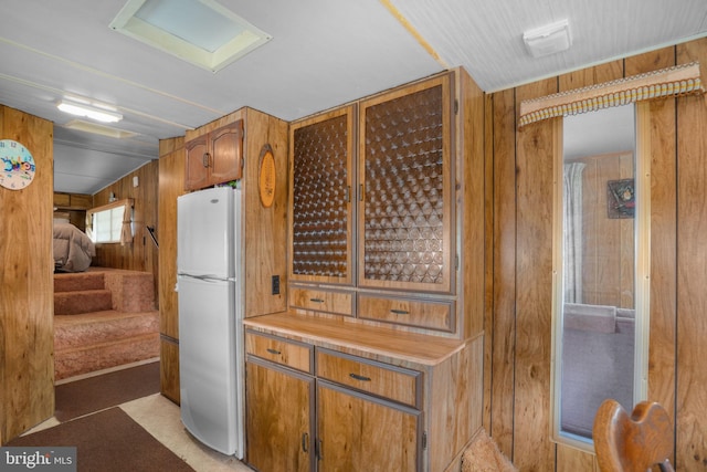 8096 Mire Pond One, Chincoteague Island, VA 23336 - kitchen with freestanding refrigerator, wooden walls, light countertops, and brown cabinetry