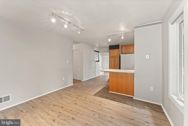402 Sugarland Run Dr, Sterling, VA 20164 - kitchen featuring freestanding refrigerator, rail lighting, brown cabinetry, light wood-type flooring, and light countertops