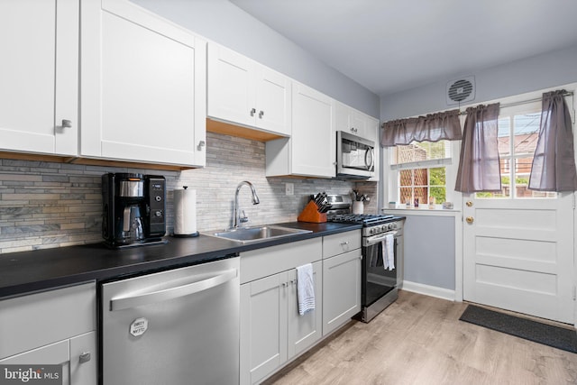 222 Blakeney Rd, Baltimore, MD 21228 - kitchen with appliances with stainless steel finishes, dark countertops, light wood finished floors, and backsplash