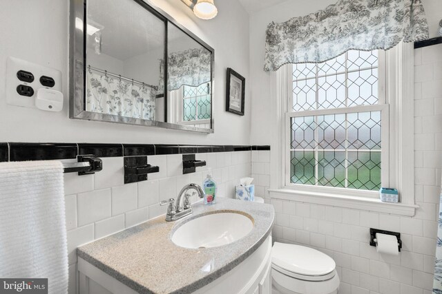 222 Blakeney Rd, Baltimore, MD 21228 - bathroom featuring tile walls, plenty of natural light, vanity, and a wainscoted wall