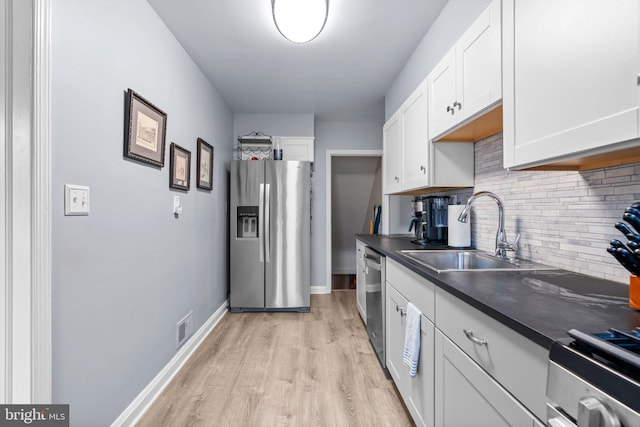 222 Blakeney Rd, Baltimore, MD 21228 - kitchen featuring stainless steel appliances, dark countertops, decorative backsplash, light wood-style floors, and white cabinets