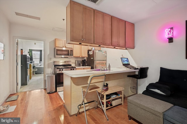 1100 Vine St Unit 1409, Philadelphia, PA 19107 - kitchen with appliances with stainless steel finishes, a peninsula, light wood finished floors, open floor plan, and a kitchen bar