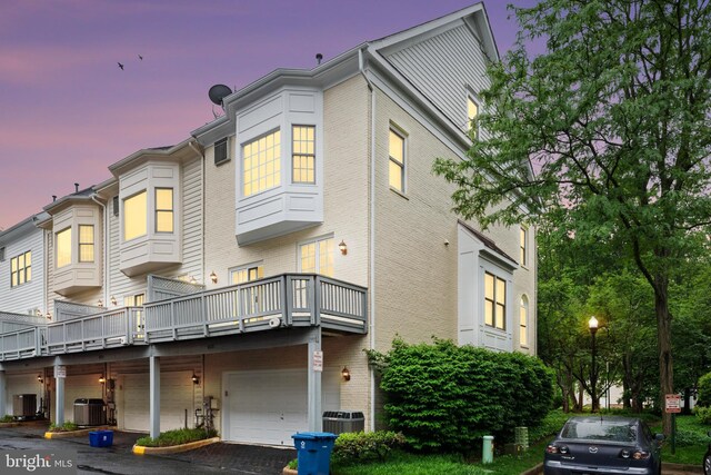 8878 Ashgrove House Ln, Vienna, VA 22182 - back of house at dusk featuring an attached garage, cooling unit, and driveway
