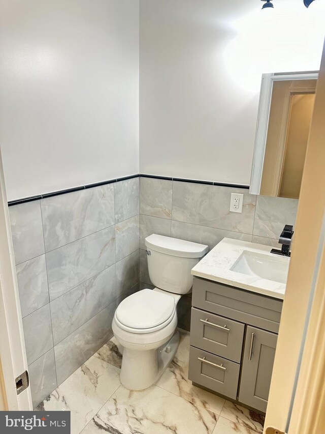 205 W Wishart St, Philadelphia, PA 19133 - half bath featuring marble look tiles, tile walls, vanity, toilet, and wainscoting