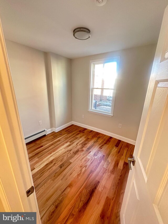 205 W Wishart St, Philadelphia, PA 19133 - spare room featuring a baseboard heating unit, wood finished floors, and baseboards