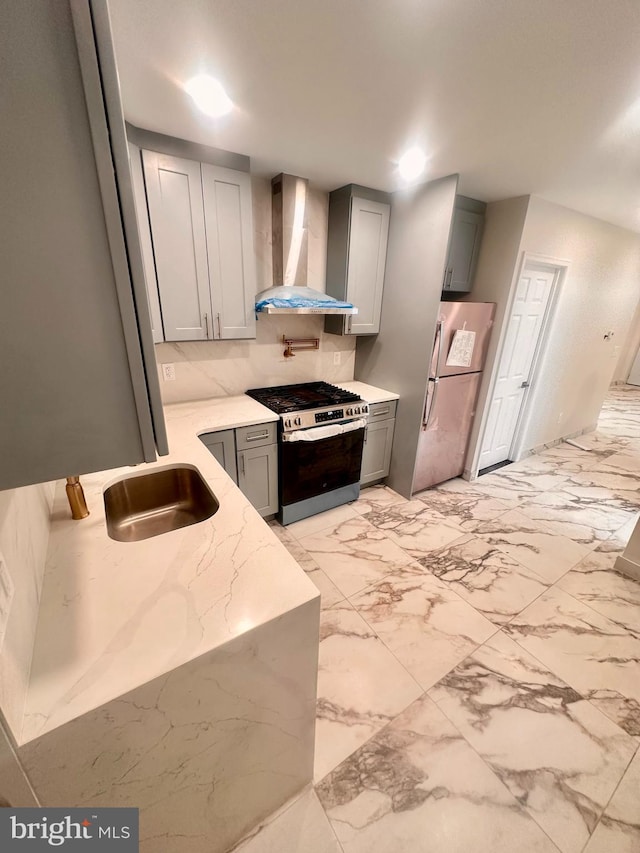 205 W Wishart St, Philadelphia, PA 19133 - kitchen with gas stove, wall chimney range hood, freestanding refrigerator, a sink, and gray cabinetry