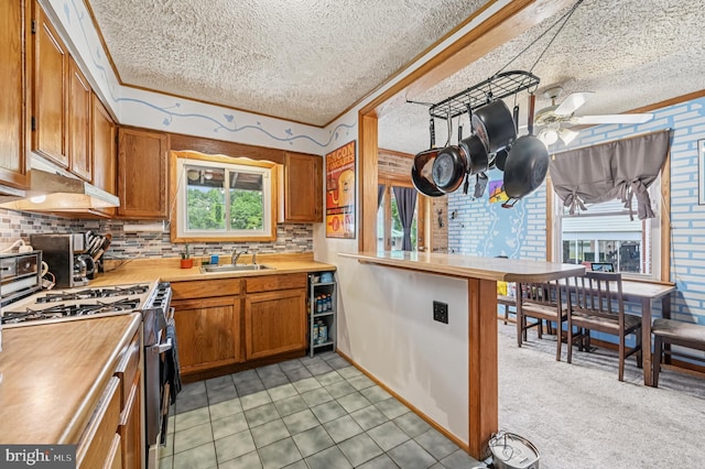 110 S Marlyn Ave, Essex, MD 21221 - kitchen featuring a textured ceiling, gas stove, brown cabinets, decorative backsplash, and a ceiling fan