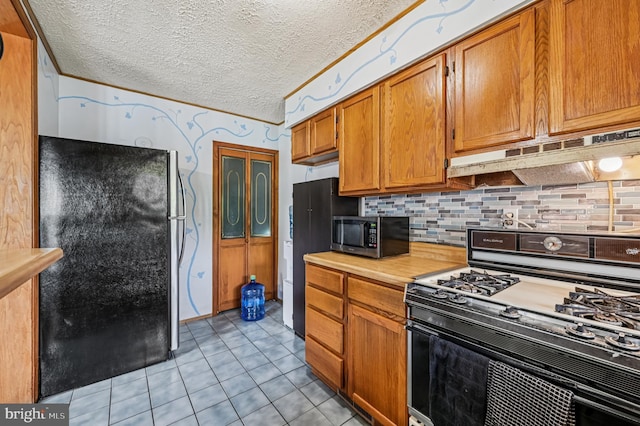110 S Marlyn Ave, Essex, MD 21221 - kitchen featuring range with gas stovetop, under cabinet range hood, light countertops, stainless steel microwave, and freestanding refrigerator