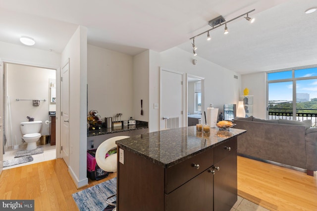 155 Potomac Psge Unit 817, Oxon Hill, MD 20745 - kitchen featuring light wood-type flooring, a kitchen island, dark brown cabinetry, dark stone countertops, and open floor plan