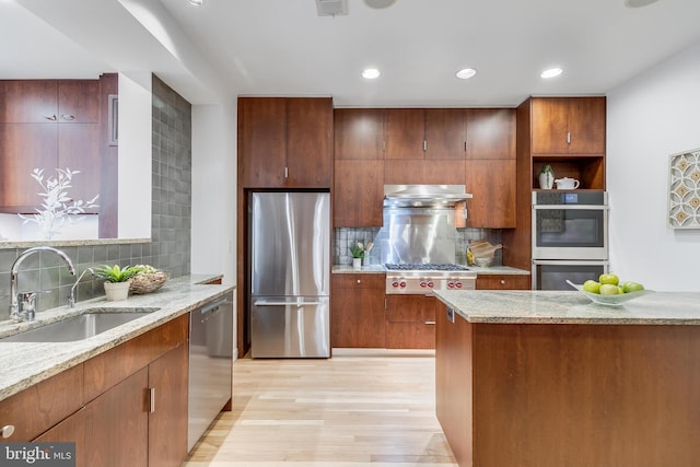 2950 Macomb St NW, Washington, DC 20008 - kitchen featuring appliances with stainless steel finishes, a sink, under cabinet range hood, light wood-style floors, and decorative backsplash