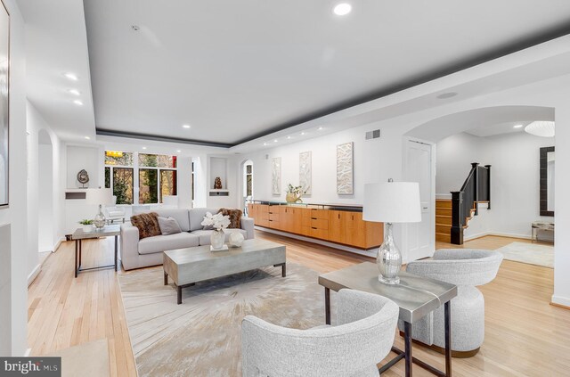 2950 Macomb St NW, Washington, DC 20008 - living room featuring arched walkways, recessed lighting, light wood-type flooring, a tray ceiling, and stairs