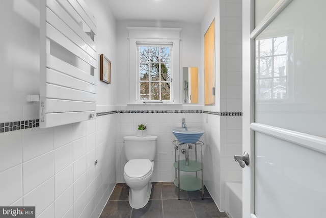2950 Macomb St NW, Washington, DC 20008 - bathroom with toilet, a sink, tile patterned floors, tile walls, and wainscoting