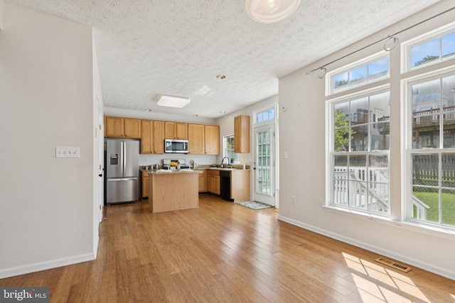 8309 Pigeon Fork Ln, Laurel, MD 20724 - kitchen with stainless steel appliances, a kitchen island, wood finished floors, light countertops, and a textured ceiling