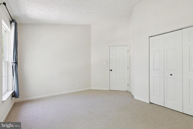 8309 Pigeon Fork Ln, Laurel, MD 20724 - unfurnished bedroom with light colored carpet, multiple windows, a closet, and a textured ceiling