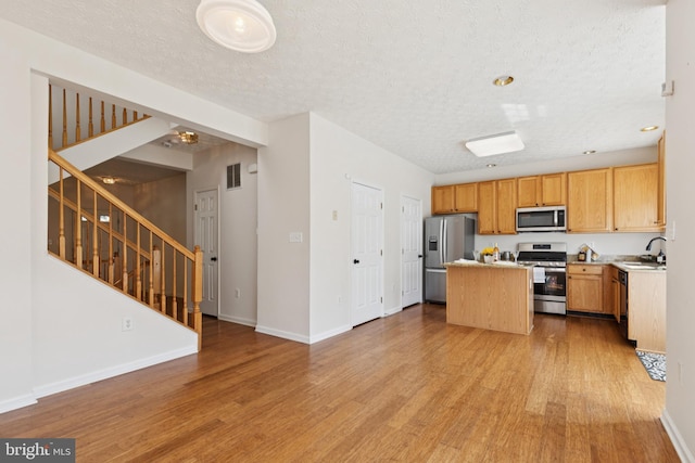 8309 Pigeon Fork Ln, Laurel, MD 20724 - kitchen with stainless steel appliances, a kitchen island, light wood-style floors, open floor plan, and light countertops