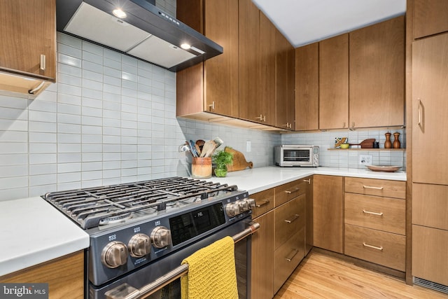 1850 Irving St NW, Washington, DC 20010 - kitchen with stainless steel range with gas cooktop, range hood, light countertops, backsplash, and light wood-style flooring