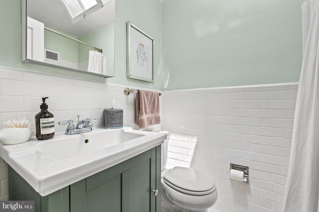 1850 Irving St NW, Washington, DC 20010 - bathroom with tile walls, vanity, a skylight, a shower with curtain, and a wainscoted wall