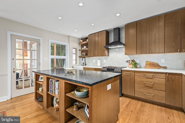 1850 Irving St NW, Washington, DC 20010 - kitchen featuring open shelves, wall chimney exhaust hood, stainless steel gas range, light wood finished floors, and backsplash