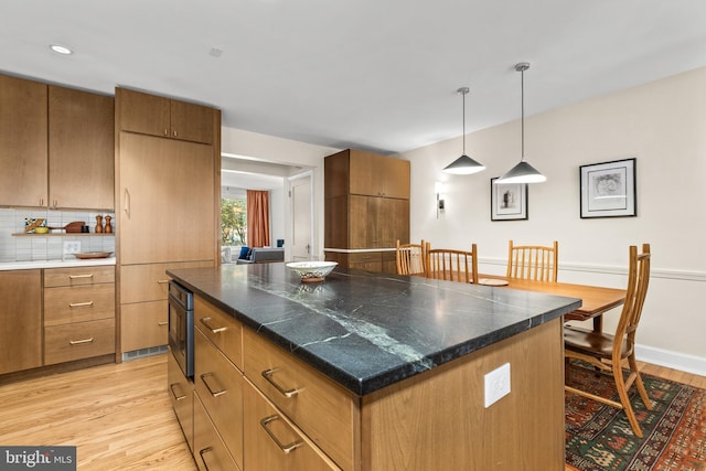 1850 Irving St NW, Washington, DC 20010 - kitchen with light wood-type flooring, brown cabinetry, a center island, decorative light fixtures, and decorative backsplash
