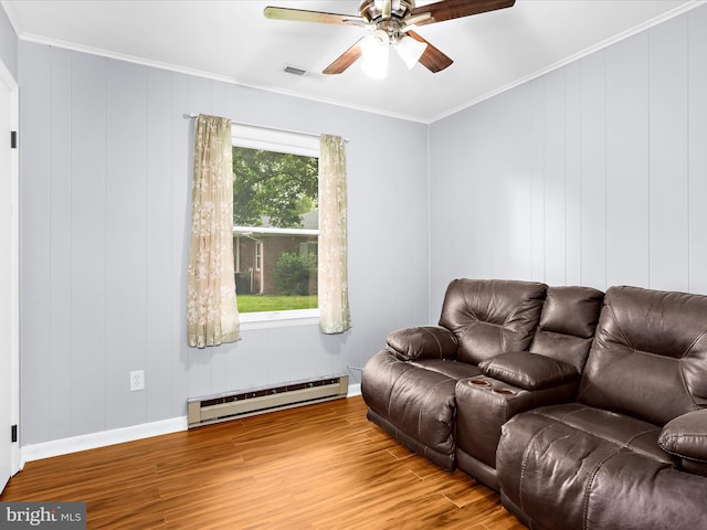213 S 6th St, Denton, MD 21629 - living room with baseboard heating, wood finished floors, a ceiling fan, ornamental molding, and a decorative wall