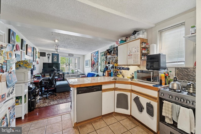 3 W Gowen Ave, Philadelphia, PA 19119 - kitchen featuring appliances with stainless steel finishes, a peninsula, a textured ceiling, open floor plan, and an office area