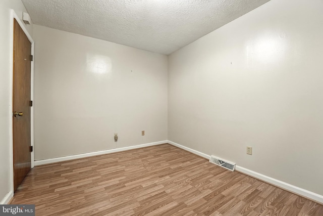 spare room featuring light wood finished floors and a textured ceiling