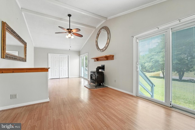 unfurnished living room with a wood stove, wood finished floors, ceiling fan, and ornamental molding