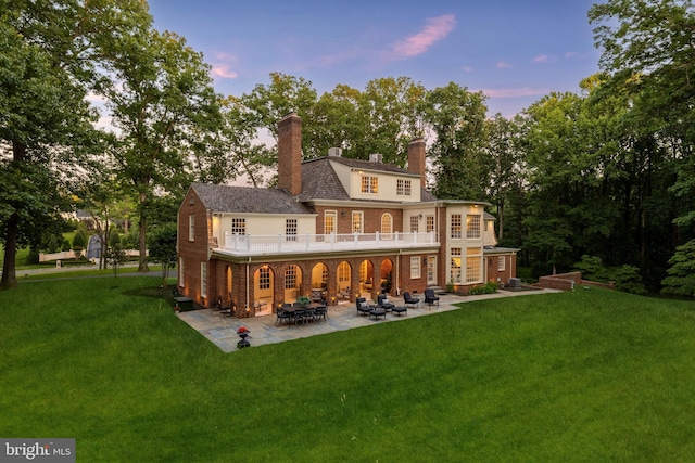 13300 Manor Stone Dr, Darnestown, MD 20874 - back of property at dusk featuring a chimney, a patio, a lawn, and brick siding