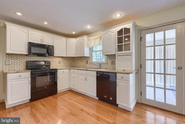1549 Willoughby Cir, Manheim, PA 17545 - kitchen featuring black appliances, light wood finished floors, white cabinets, tasteful backsplash, and glass insert cabinets