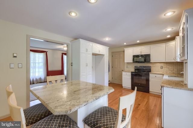 1549 Willoughby Cir, Manheim, PA 17545 - kitchen featuring black appliances, light wood-style flooring, tasteful backsplash, white cabinetry, and light stone counters