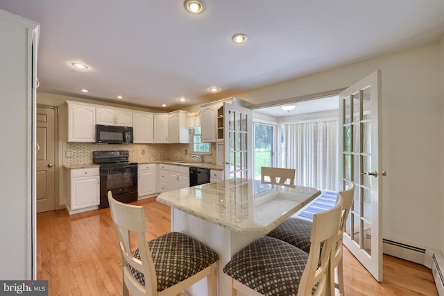 1549 Willoughby Cir, Manheim, PA 17545 - kitchen with black appliances, a breakfast bar area, white cabinets, backsplash, and recessed lighting