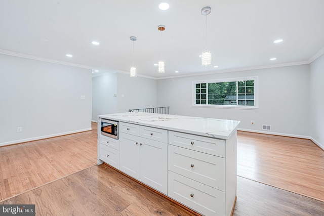 4721 Springbrook Dr, Annandale, VA 22003 - kitchen with stainless steel microwave, ornamental molding, white cabinetry, light wood-style floors, and pendant lighting