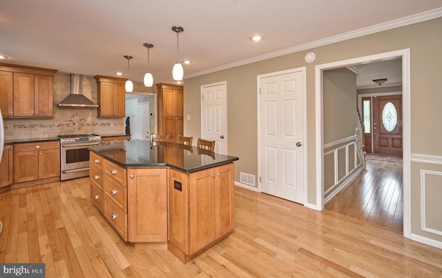 365 Newgate Rd, Langhorne, PA 19047 - kitchen featuring stainless steel gas stove, wall chimney exhaust hood, light wood-type flooring, a center island with sink, and brown cabinetry