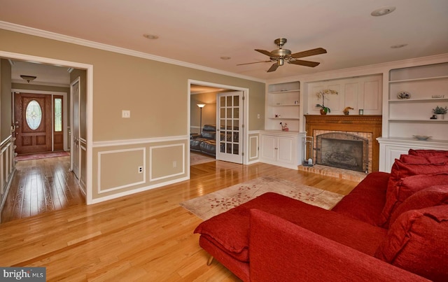 365 Newgate Rd, Langhorne, PA 19047 - living area featuring light wood-style floors, ceiling fan, ornamental molding, a wainscoted wall, and a brick fireplace