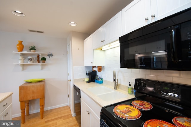 304 Academy St Unit 202, Cambridge, MD 21613 - kitchen with black appliances, decorative backsplash, white cabinetry, light wood-style flooring, and light countertops