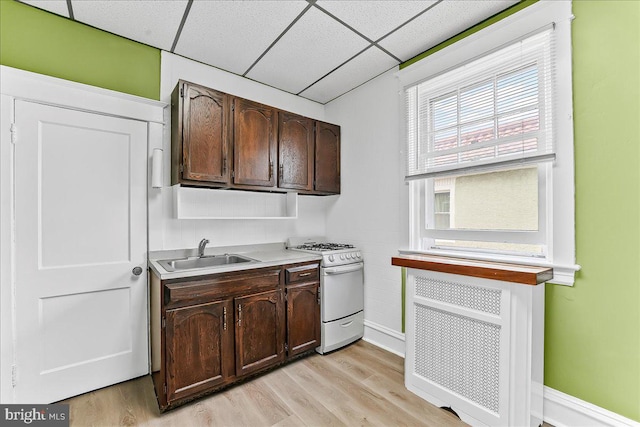736 Poplar St, Sharon Hill, PA 19079 - kitchen featuring white gas range, a sink, dark brown cabinets, light wood-style flooring, and a paneled ceiling