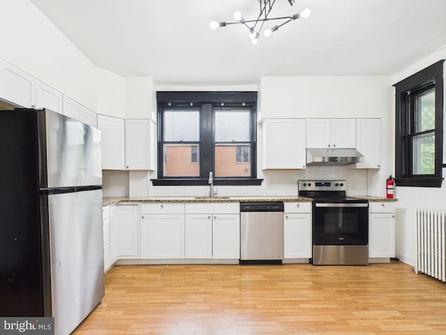 3437 Market St, Camp Hill, PA 17011 - kitchen with stainless steel appliances, under cabinet range hood, radiator heating unit, light wood-style flooring, and white cabinets