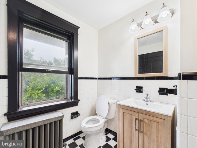 3437 Market St, Camp Hill, PA 17011 - bathroom with radiator heating unit, vanity, tile walls, a wainscoted wall, and tile patterned floors