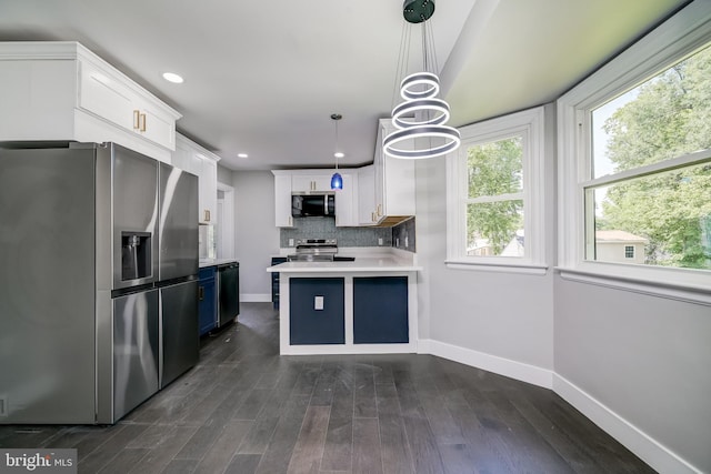 8808 Edmonston Rd, College Park, MD 20740 - kitchen with appliances with stainless steel finishes, a peninsula, light countertops, white cabinets, and dark wood-style floors