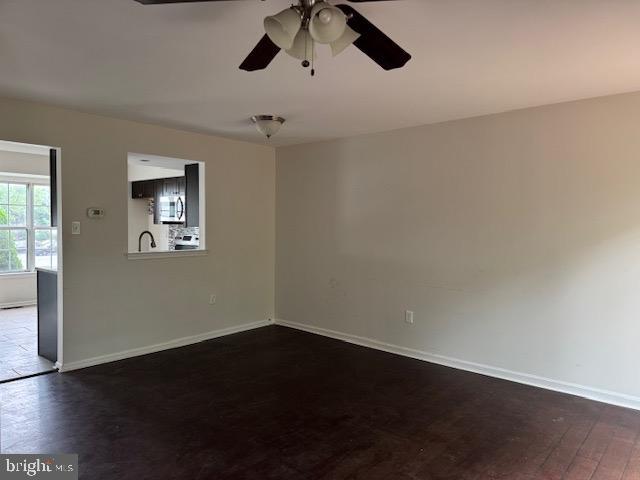 7849 Hidden Crk Unit 24, Baltimore, MD 21226 - spare room with dark wood-style floors, a ceiling fan, and baseboards