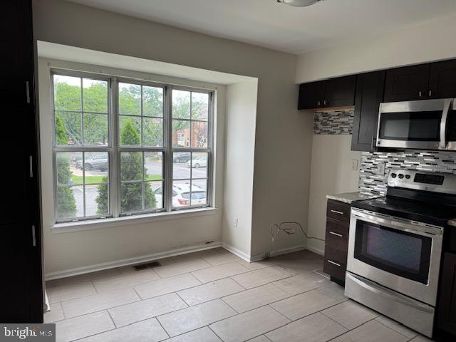 7849 Hidden Crk Unit 24, Baltimore, MD 21226 - kitchen featuring stainless steel appliances, healthy amount of natural light, backsplash, and baseboards