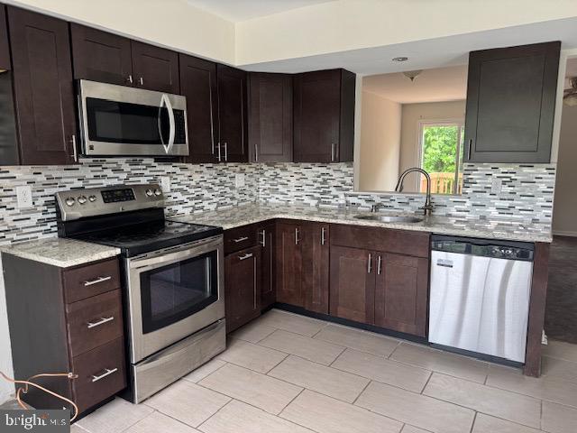 7849 Hidden Crk Unit 24, Baltimore, MD 21226 - kitchen with stainless steel appliances, a sink, tasteful backsplash, and light stone countertops