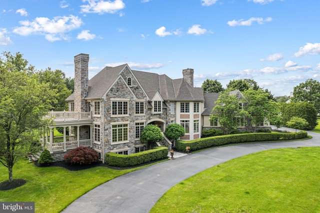 1214 Hunt Seat Dr, Lower Gwynedd, PA 19002 - view of front facade with stone siding, a chimney, a front yard, and a balcony