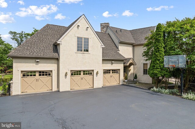 1214 Hunt Seat Dr, Lower Gwynedd, PA 19002 - view of side of property with stucco siding, a shingled roof, a chimney, and asphalt driveway