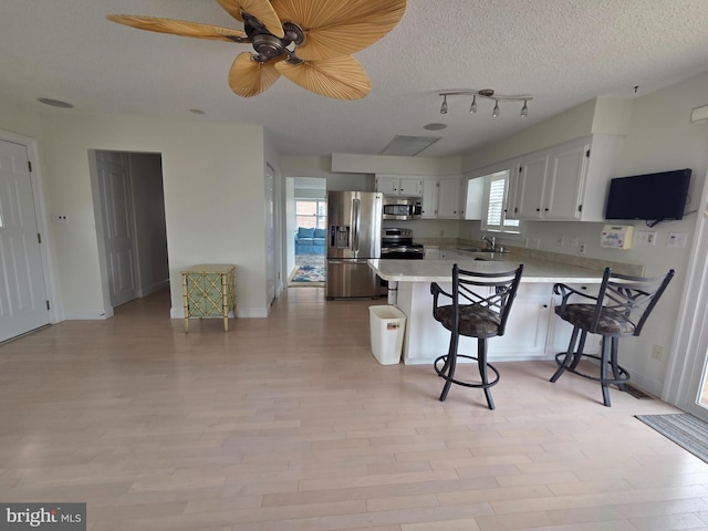 156 Captains Quarters Rd, Ocean City, MD 21842 - kitchen featuring appliances with stainless steel finishes, a peninsula, light countertops, a kitchen breakfast bar, and white cabinets