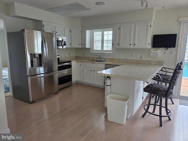 156 Captains Quarters Rd, Ocean City, MD 21842 - kitchen featuring stainless steel appliances, a peninsula, light wood-type flooring, light countertops, and white cabinets
