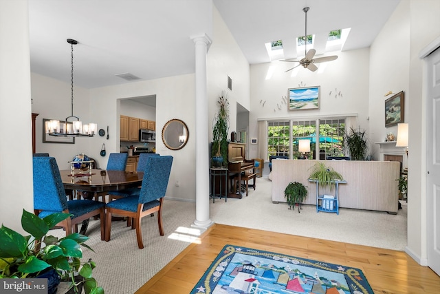 128 Rowan Ct, Manahawkin, NJ 08050 - dining space featuring light wood-type flooring, a skylight, a chandelier, ceiling fan, and a high ceiling