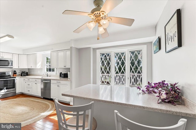 16 Judith Ln, Thornton, PA 19373 - kitchen featuring stainless steel appliances, white cabinetry, a breakfast bar area, light wood finished floors, and light stone counters